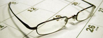 Pair of eyeglasses sitting on a monthly calendar